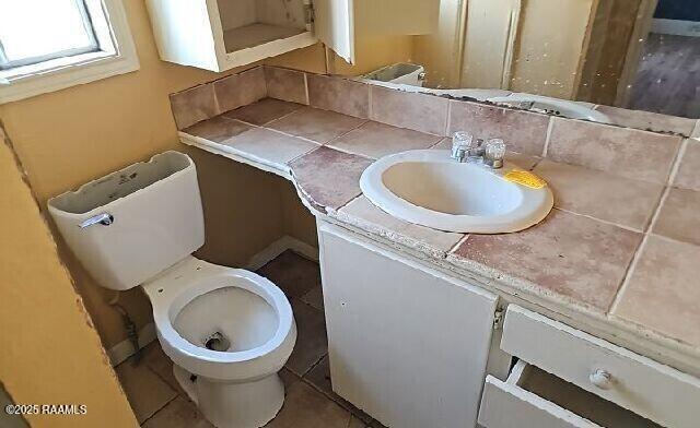 half bathroom featuring vanity, tile patterned flooring, and toilet