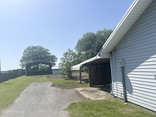 view of home's exterior featuring a carport, fence, and a lawn