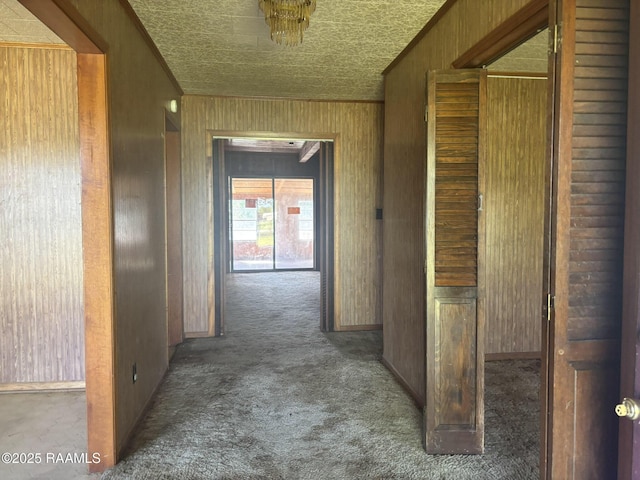 hallway featuring carpet floors, baseboards, and wood walls