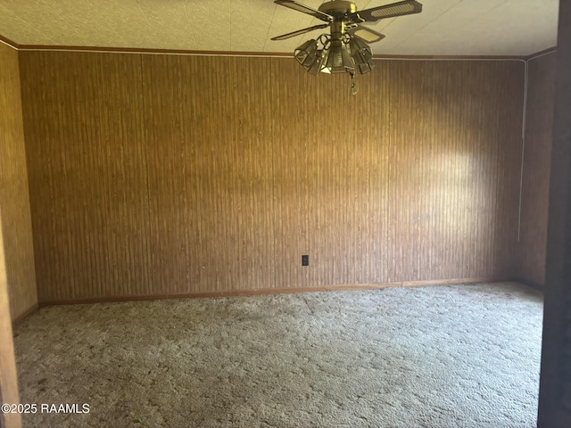 spare room with wood walls, a ceiling fan, and carpet floors
