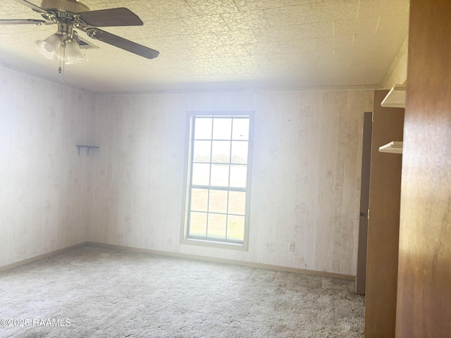 carpeted spare room featuring baseboards and a ceiling fan