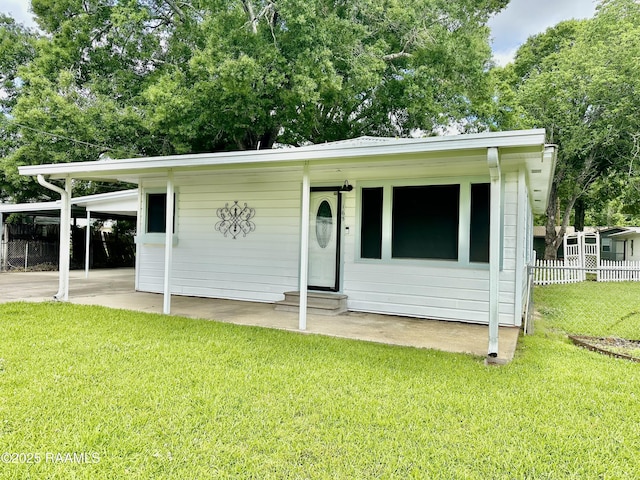 view of front of home featuring entry steps, a front lawn, fence, and an attached carport