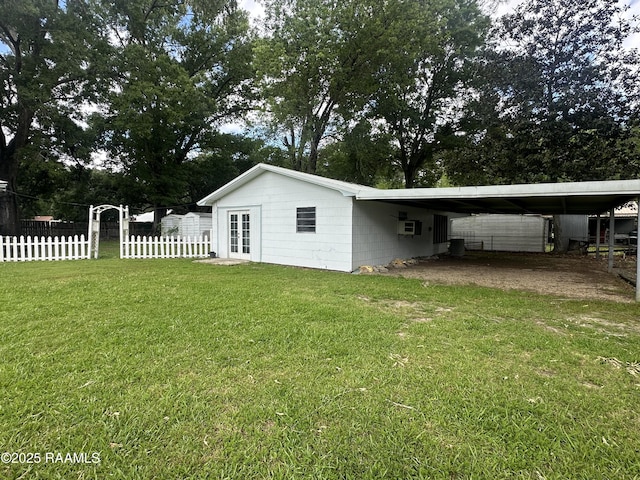 exterior space featuring french doors, fence, an attached carport, and a lawn