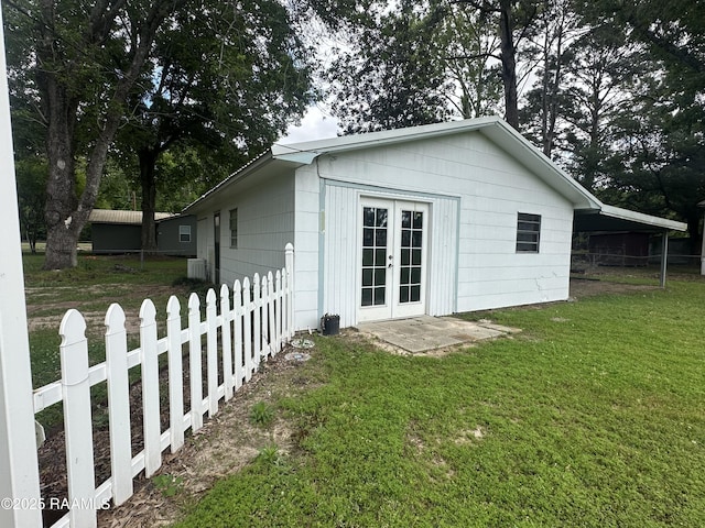 view of side of property with central AC, french doors, fence, and a yard