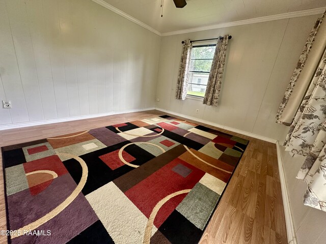 spare room featuring baseboards, ornamental molding, a ceiling fan, and wood finished floors