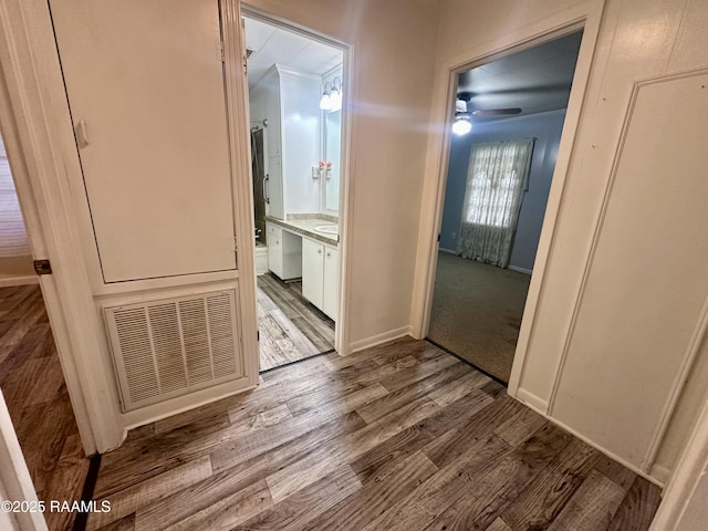 hallway with visible vents, baseboards, and wood finished floors