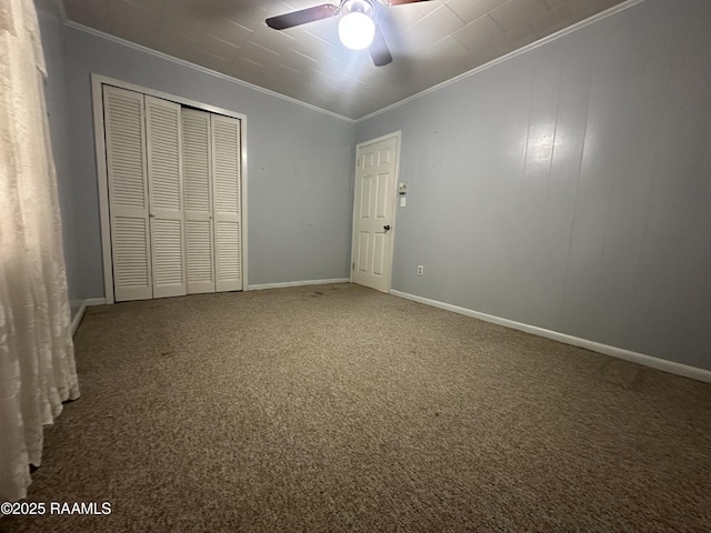 unfurnished bedroom featuring crown molding, ceiling fan, carpet, a closet, and baseboards