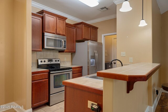 111 Bottle Brush Ln, Carencro, LA 70520 - kitchen featuring crown molding, a peninsula, a breakfast bar, tile countertops, and stainless steel appliances
