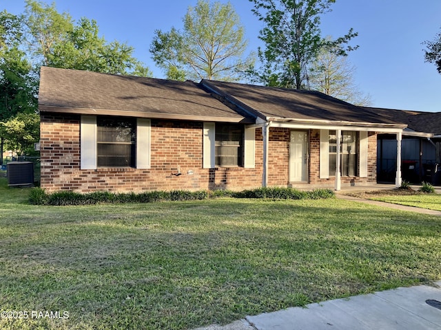 single story home featuring a front yard, a shingled roof, brick siding, and cooling unit
