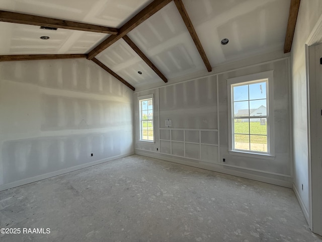 empty room featuring baseboards and vaulted ceiling with beams