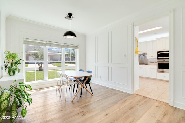 dining room with crown molding, visible vents, and light wood-style flooring