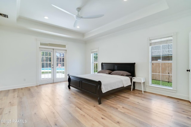 bedroom featuring access to outside, french doors, light wood-type flooring, a tray ceiling, and visible vents