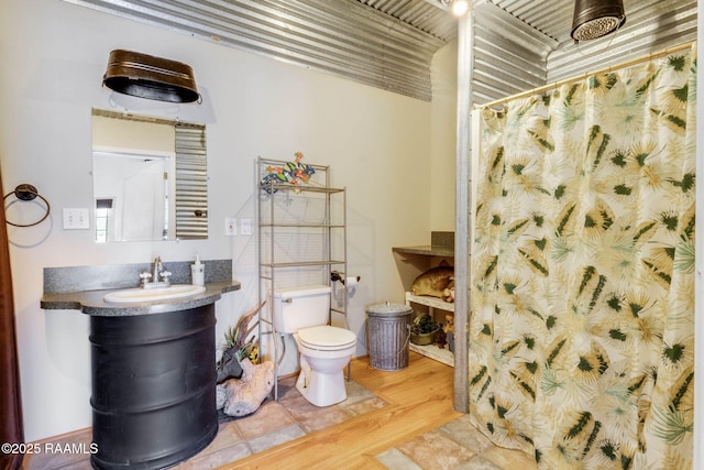 bathroom featuring toilet, a shower with curtain, and wood finished floors