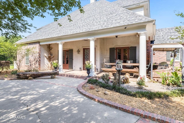 view of front facade with stucco siding and a shingled roof