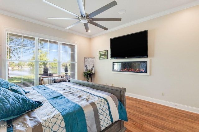 bedroom with ornamental molding, baseboards, multiple windows, and wood finished floors