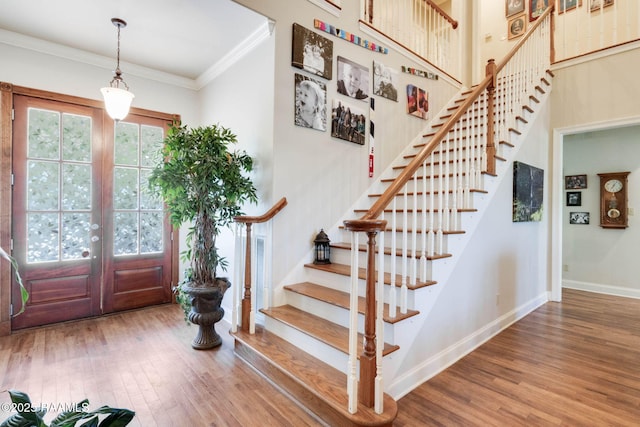 foyer entrance featuring baseboards, wood finished floors, stairs, and crown molding