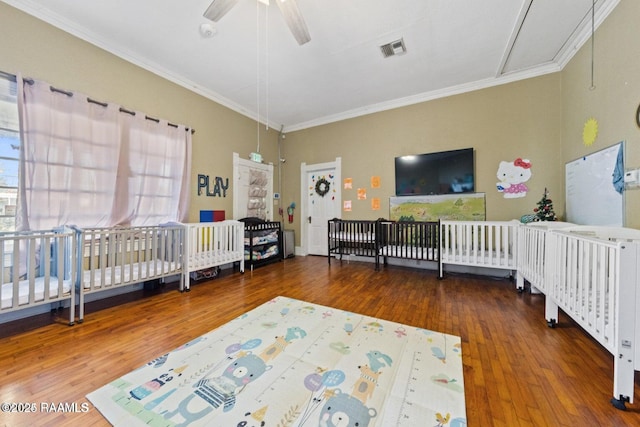 bedroom with ornamental molding, wood finished floors, multiple windows, and visible vents