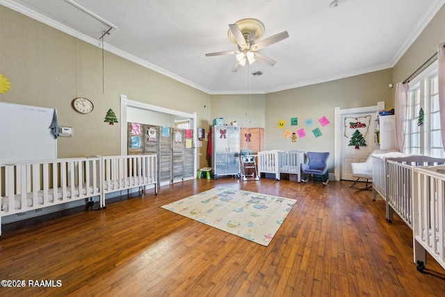 bedroom featuring crown molding, attic access, hardwood / wood-style flooring, and multiple windows