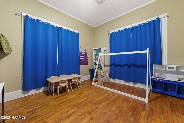 playroom with wood-type flooring, baseboards, and ornamental molding