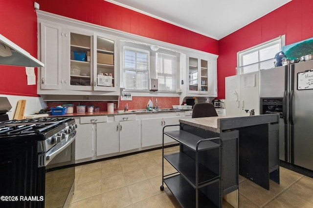 kitchen with refrigerator with ice dispenser, extractor fan, glass insert cabinets, white cabinets, and stainless steel range with gas stovetop