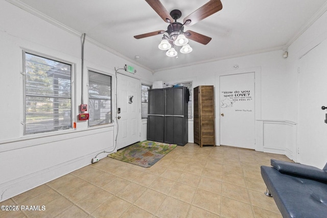 foyer with a ceiling fan, ornamental molding, light tile patterned flooring, and plenty of natural light