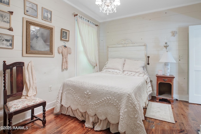bedroom with wooden walls, an inviting chandelier, and hardwood / wood-style floors