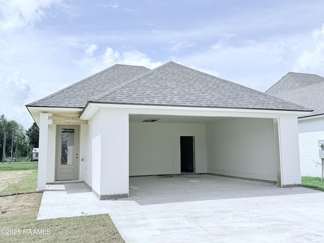 ranch-style house with brick siding, concrete driveway, roof with shingles, and a carport