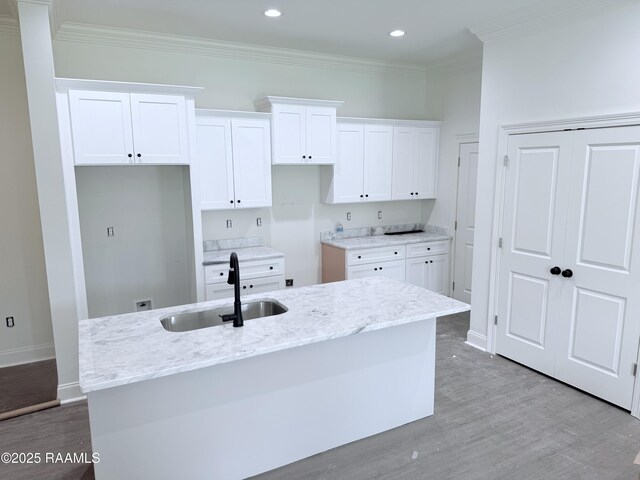 214 Berchman Oaks Dr, Lafayette, LA 70506 - kitchen with a sink, white cabinets, light wood finished floors, a center island with sink, and ornamental molding