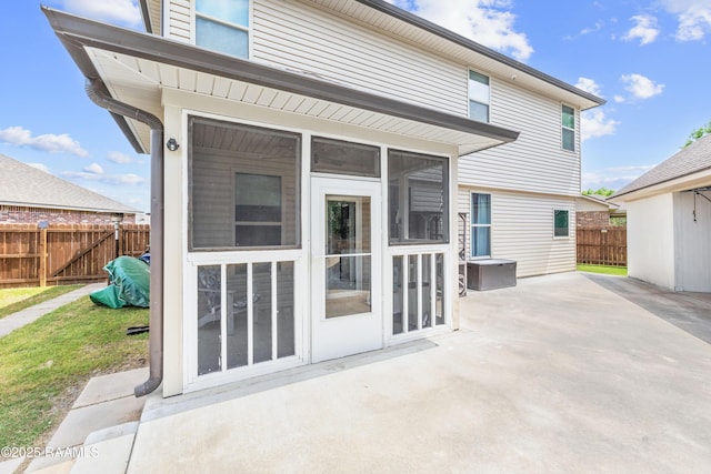 rear view of property featuring a patio area, a sunroom, and fence