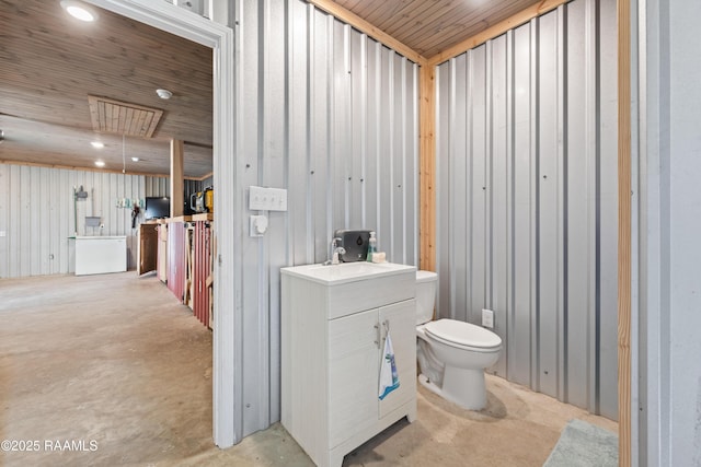 bathroom with concrete floors, toilet, vanity, and recessed lighting