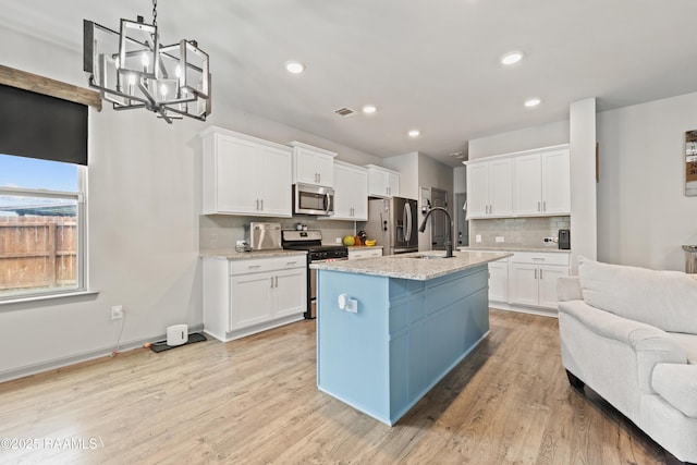 kitchen featuring stainless steel appliances, backsplash, a sink, a chandelier, and white cabinetry
