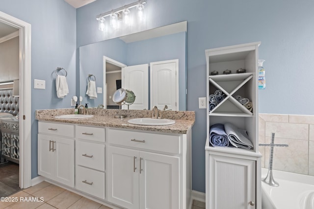 bathroom with double vanity, a garden tub, tile patterned flooring, and a sink