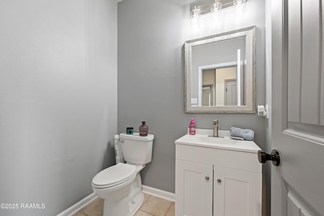 half bathroom featuring baseboards, tile patterned floors, vanity, and toilet