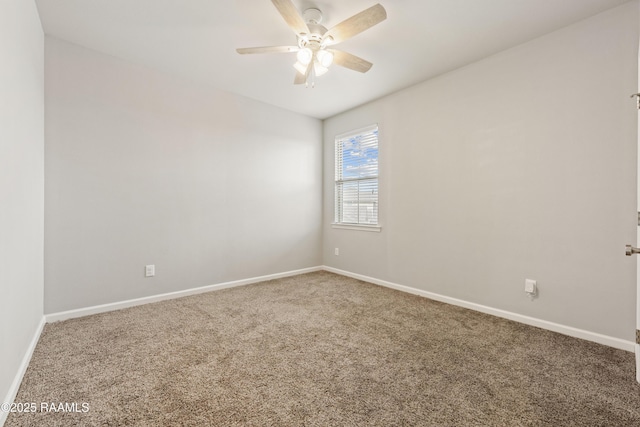 carpeted spare room with a ceiling fan and baseboards