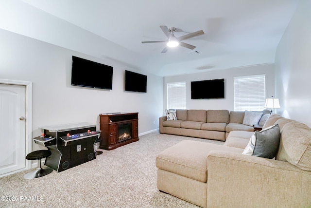 carpeted living area featuring a glass covered fireplace, visible vents, a ceiling fan, and baseboards