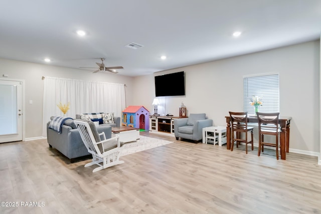 living room featuring light wood-type flooring, a ceiling fan, visible vents, and recessed lighting