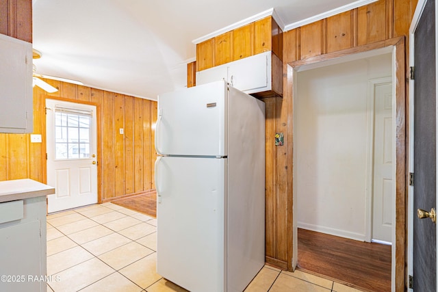 204 Eastland Dr, Lafayette, LA 70503 - kitchen with light countertops, light tile patterned floors, baseboards, wood walls, and freestanding refrigerator