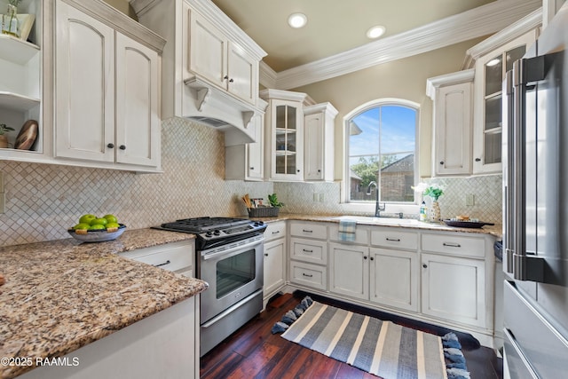 kitchen with tasteful backsplash, dark wood-style flooring, stainless steel gas range oven, glass insert cabinets, and ornamental molding