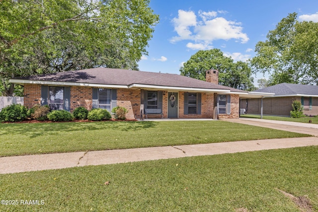ranch-style home with covered porch, a chimney, a front yard, brick siding, and concrete driveway