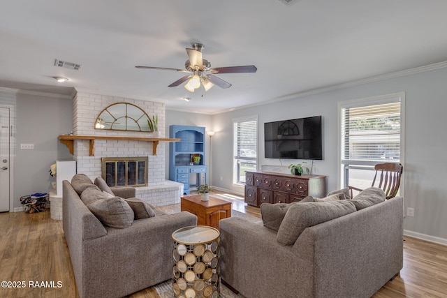 living room with visible vents, ornamental molding, ceiling fan, and wood finished floors