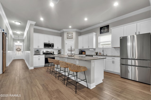 113 Spider Lily Ln, Lafayette, LA 70508 - kitchen featuring a center island, a sink, a breakfast bar area, stainless steel appliances, and backsplash