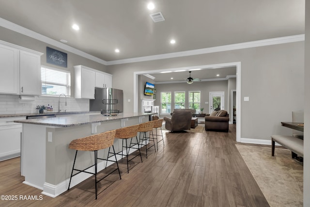 113 Spider Lily Ln, Lafayette, LA 70508 - kitchen with open floor plan, ceiling fan, freestanding refrigerator, visible vents, and a kitchen island