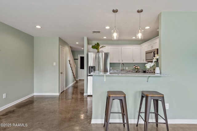 1612 Dehart Dr Unit A, New Iberia, LA 70560 - kitchen with white cabinets, a kitchen breakfast bar, visible vents, concrete flooring, and appliances with stainless steel finishes