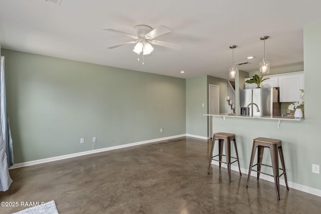 1612 Dehart Dr Unit A, New Iberia, LA 70560 - kitchen with concrete flooring, stainless steel fridge, a kitchen bar, baseboards, and white cabinetry