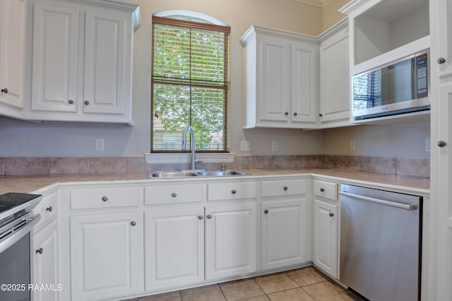kitchen with white cabinets, appliances with stainless steel finishes, a sink, light countertops, and light tile patterned floors