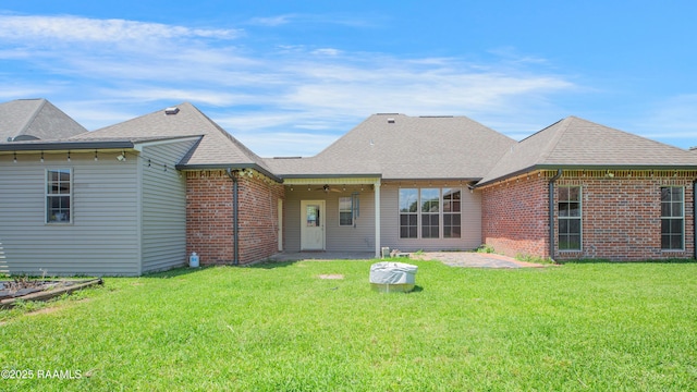 back of property with a lawn, brick siding, a ceiling fan, and a patio area