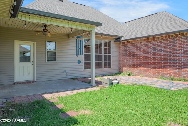 back of property featuring a yard, ceiling fan, a patio area, and roof with shingles