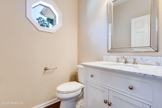 bathroom featuring toilet, vanity, and baseboards