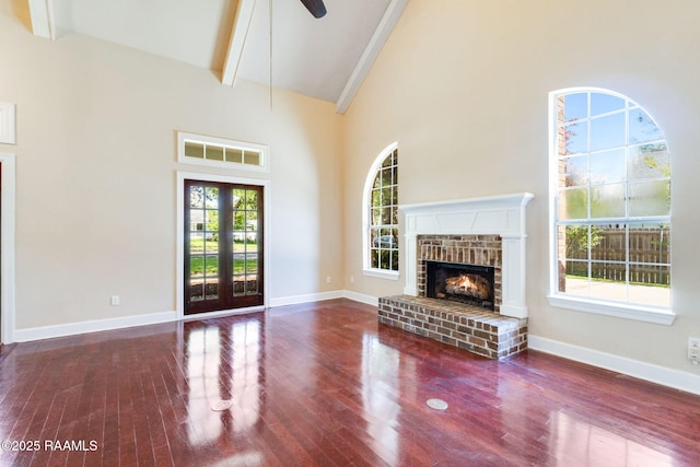 unfurnished living room with beamed ceiling, a ceiling fan, wood finished floors, a brick fireplace, and high vaulted ceiling