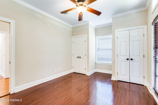 unfurnished bedroom with multiple windows, baseboards, wood finished floors, and crown molding